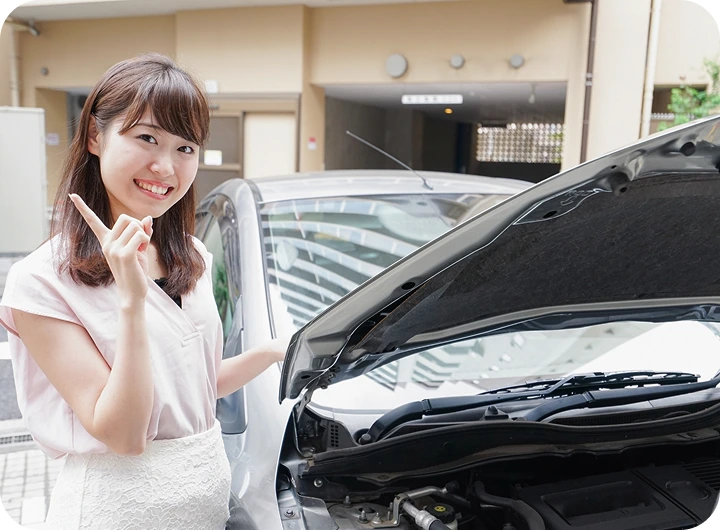 ボンネットを開けた車の前で笑顔を見せる女性