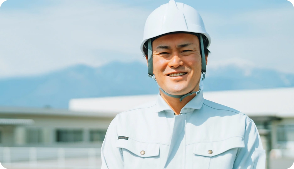 ヘルメットをかぶり笑顔を見せる作業員