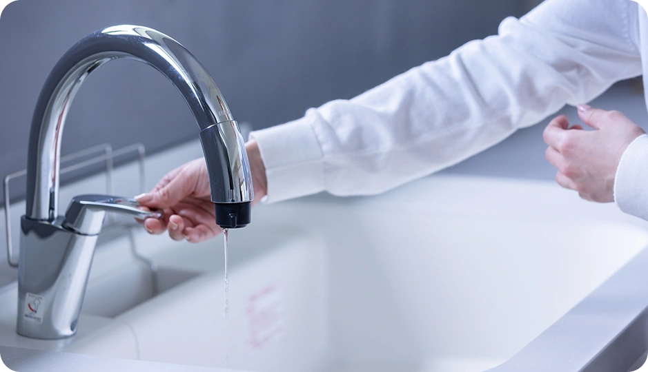 シンクで水道のレバーを操作する人の手